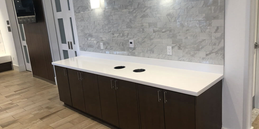 White countertop, dark cabinets, marble tile backsplash