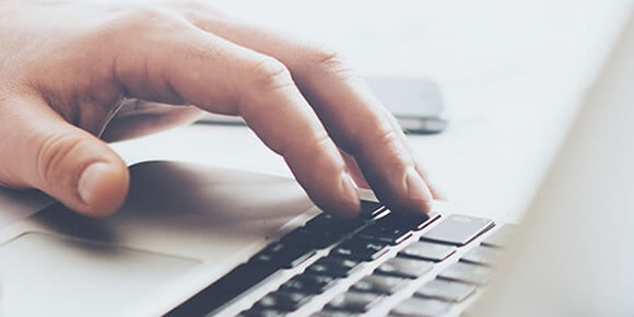 Closeup of hand typing on laptop keyboard