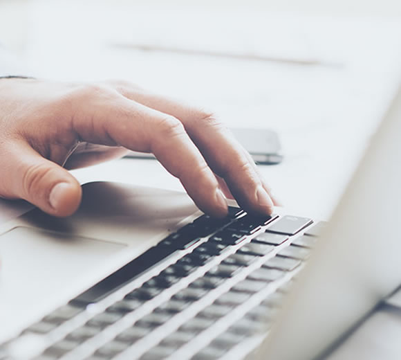 Closeup of hand typing on laptop keyboard